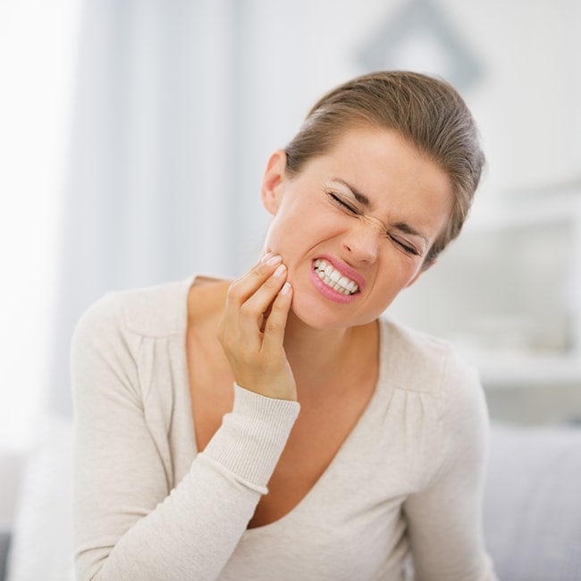 Women holding her mouth in pain because of a dental emergency.